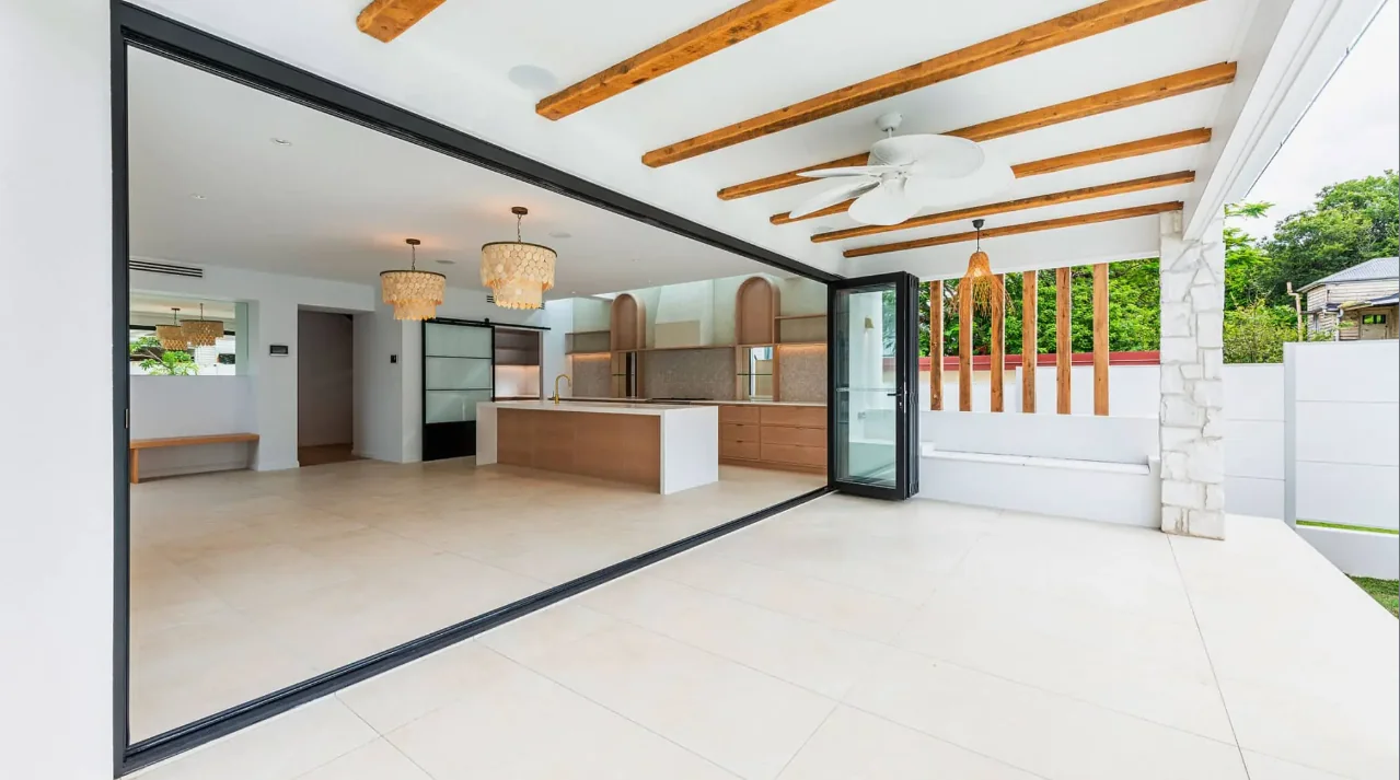 Aluminium bi-fold doors folded open between a living room and covered deck