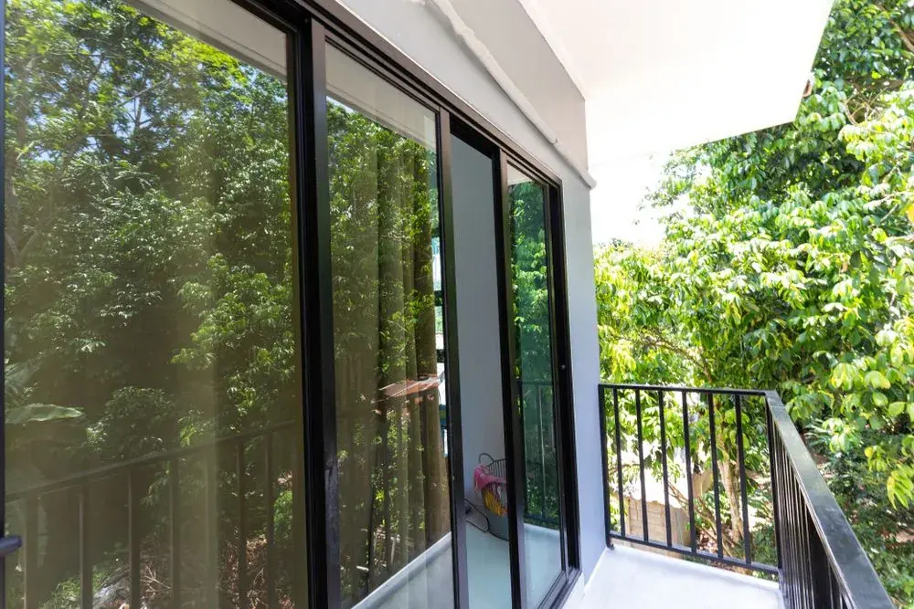 Large aluminium framed sliding glass doors beside a balcony