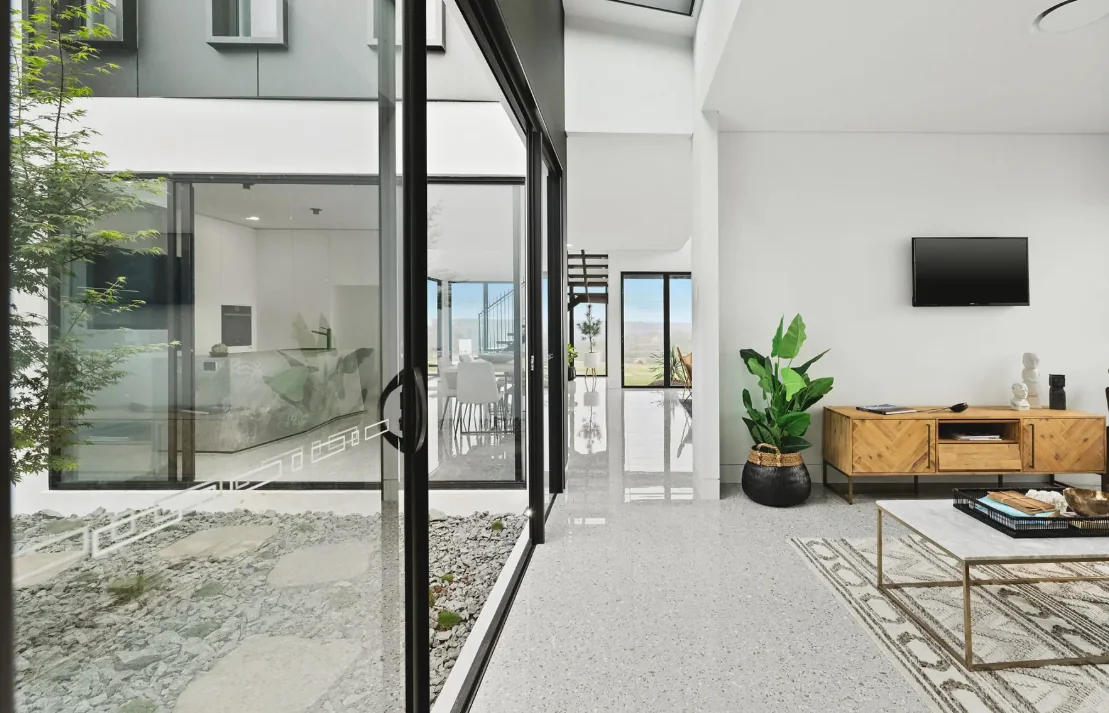 Open-plan kitchen and dining area opening to a pool deck through wide aluminium sliding doors